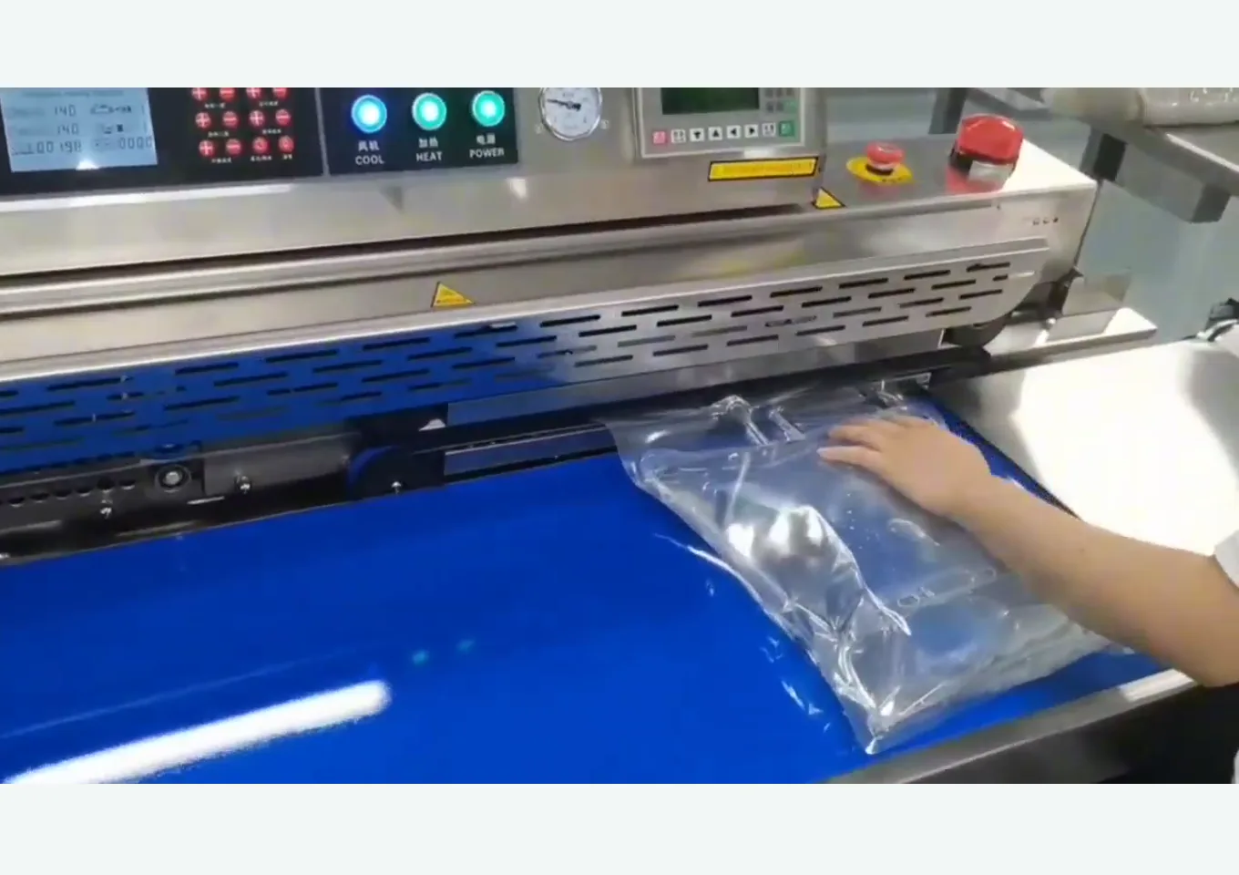 Close-up of operator feeding transparent unbranded bag mouth into the continuous processing area