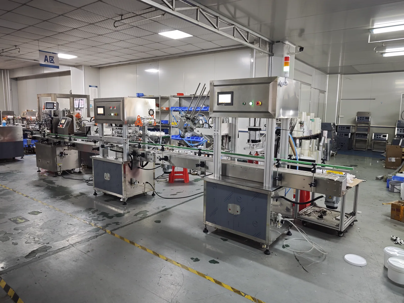 Side-front factory photo of filling, press capping, sealing equipment arranged along the same conveying direction