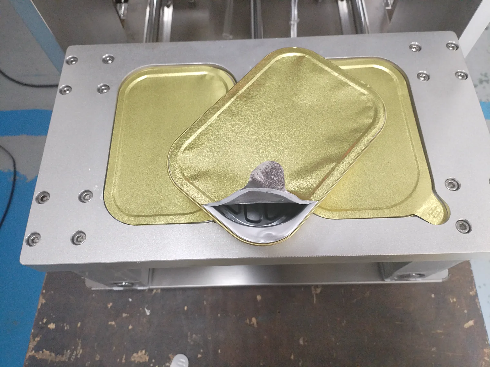 Close-up of gold aluminum foil trays in dual-cavity fixture and seal effect after film removal