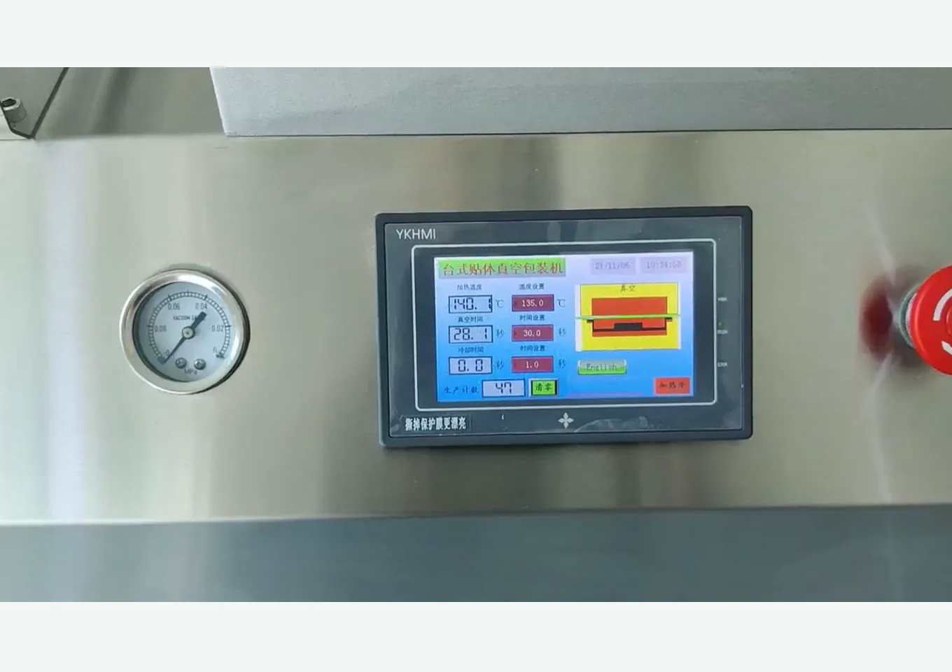 Close-up of vacuum skin packaging machine touch screen, vacuum pressure gauge, and emergency stop button control area